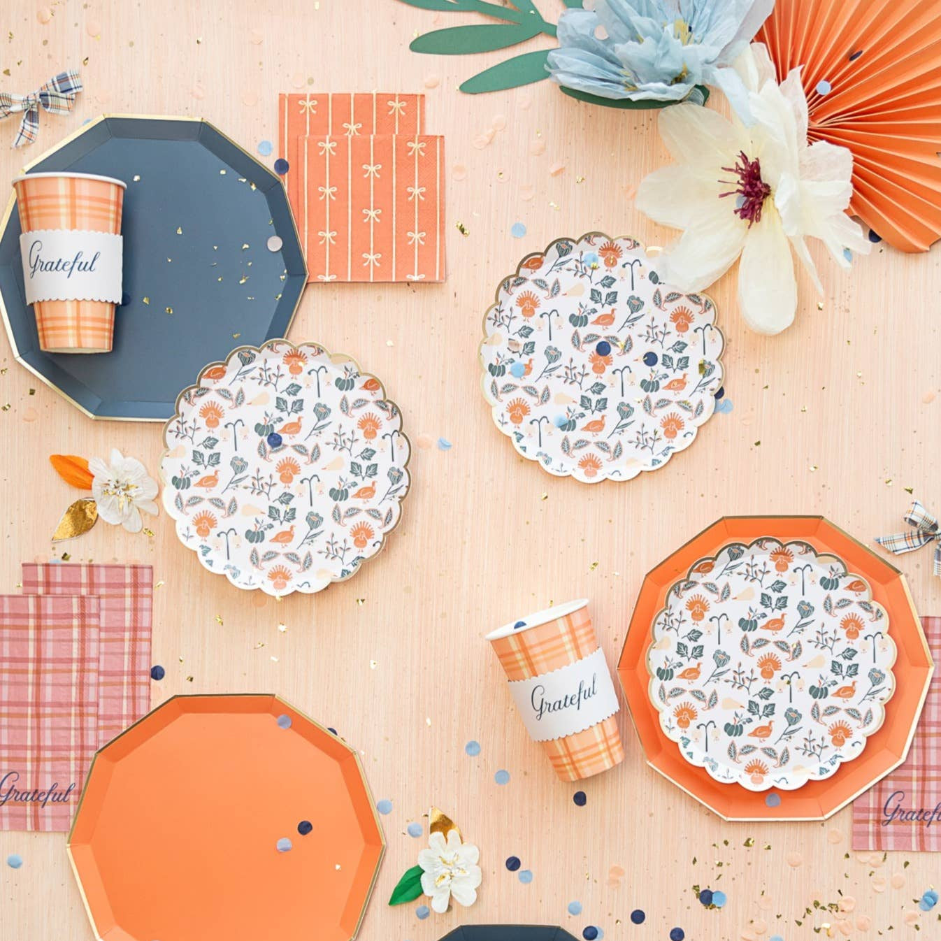 Thanksgiving tablescape with Sunkissed Orange bow napkins, orange plates, plaid cups, and fall confetti