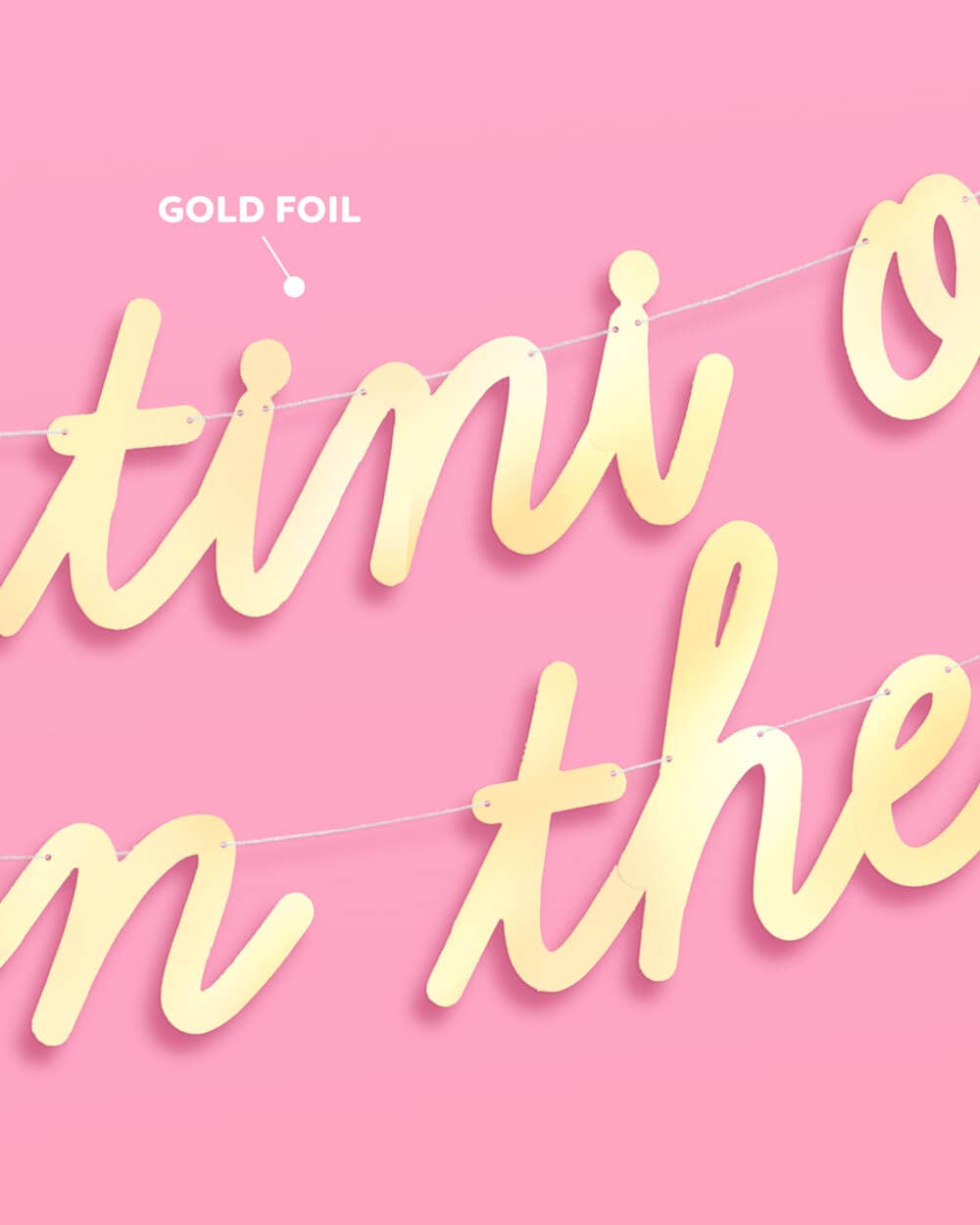 Close-up of gold foil finish on Tini One on the Way banner lettering on pink background