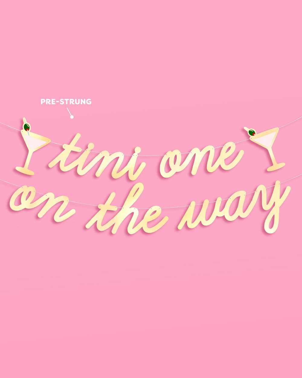 Tini One on the Way gold foil banner pre-strung on gold cords with martini glass icons on pink background