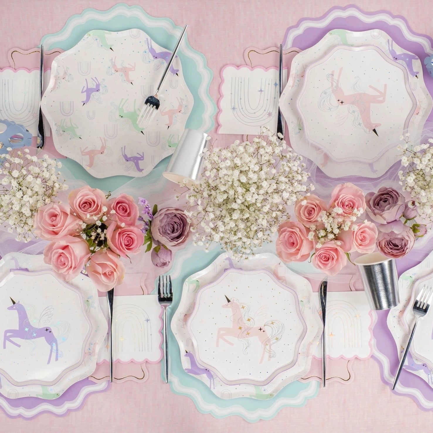Place settings with mixed unicorn designs and rainbow napkins.