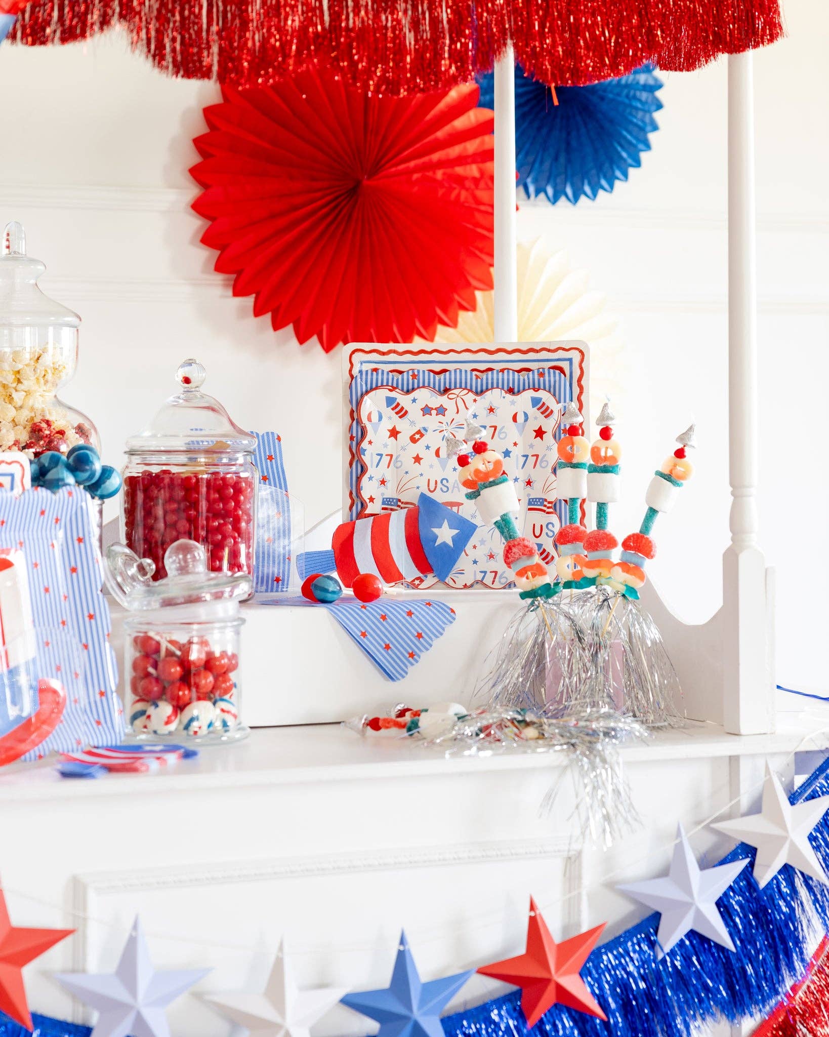 USA icons scalloped paper plate displayed on patriotic party cart with candy jars, red and blue paper fans, star garland, and candy kabobs