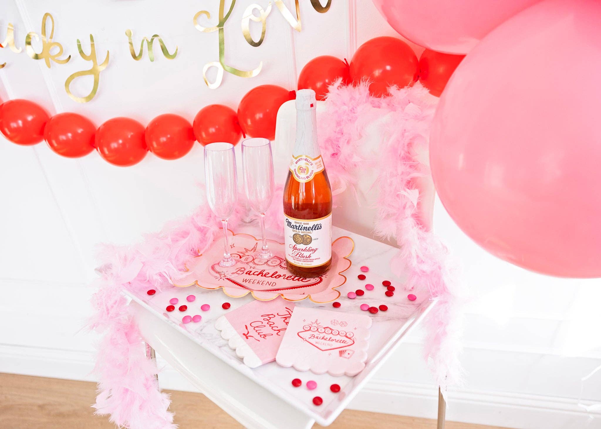 Vegas bachelorette napkins styled on a bar cart with pink champagne and a Lucky in Love banner.