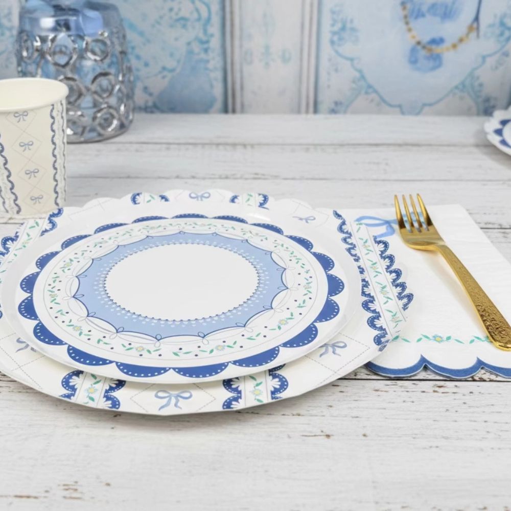 Layered blue bow plates styled with a white scalloped napkin and gold fork