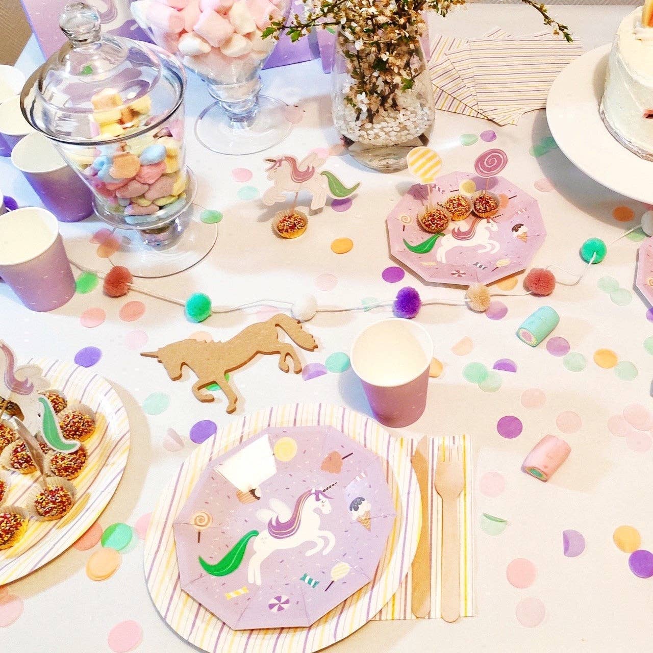 Full party table spread with unicorn plates, treats, and pastel decorations