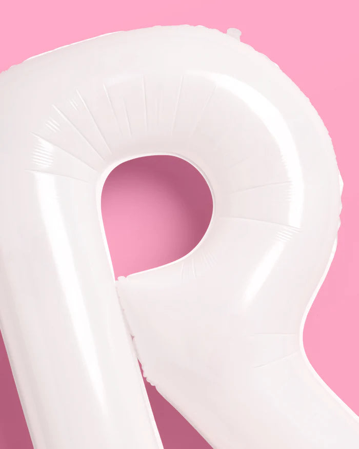 Close-up detail of white matte mylar letter R balloon showing smooth matte finish and seams on pink background